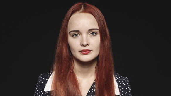 Porträt einer Frau mit langen rotbraunen Haaren isoliert auf schwarzem Hintergrund. Nahaufnahme einer Frau, die in die Kamera schaut. - JLPSF17858