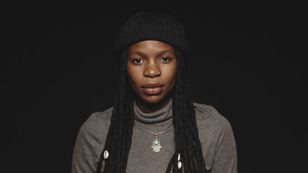 Porträt einer Afrikanerin im T-Shirt mit langen Dreadlocks. Porträt einer Afrikanerin isoliert auf schwarzem Hintergrund. - JLPSF17861
