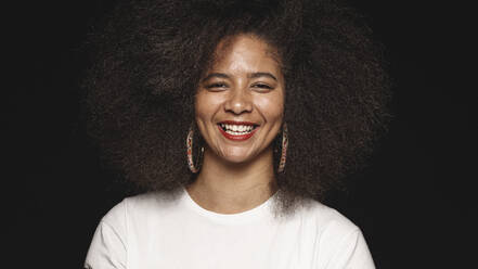 Glückliche Afroamerikanerin mit Afrofrisur isoliert auf schwarzem Hintergrund. Nahaufnahme einer lächelnden Frau, die in die Kamera schaut. - JLPSF17871