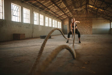 Fitness Frau Training mit Kampf Seile in verlassenen Lagerhaus. muskulöse Frau tun Kampf Seil Training. - JLPSF18026