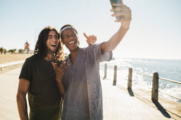 Young friends doing selfie standing on a road by the beach. Friends make a selfie on the seaside hangout. - JLPSF18046