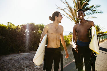 Zwei männliche Surfer, die Surfbretter tragen und zum Meer gehen. Männliche Freunde, die auf dem Wasser surfen. - JLPSF18057