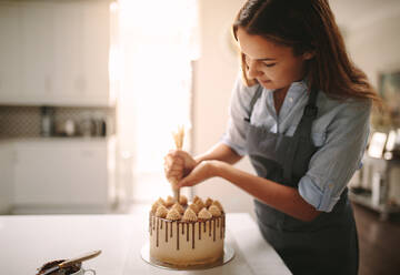 Eine Frau dekoriert einen Schokoladenkuchen in der Küche. Eine Köchin macht einen Kuchen zu Hause. - JLPSF18118