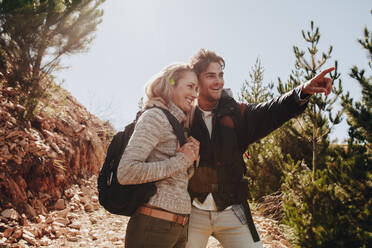 Young couple hiking on mountain trails. Man showing something to woman while mountain hike. - JLPSF18165