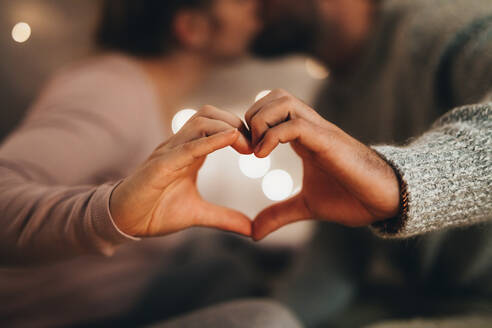 Romantic couple making the symbol of heart with their hands. Man and woman kissing each other while making the love sign with their hands. - JLPSF18210