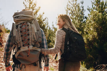 Rückansicht eines wandernden Paares junger Leute. Junger Mann und Frau mit Rucksack wandernd auf einem Berg. - JLPSF18213