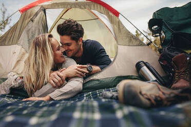 Glücklicher Mann und Frau, die einen romantischen Moment in einem Zelt verbringen, ein Paar beim Camping in der Natur. - JLPSF18234