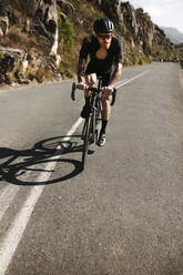 Berufsradfahrer, der mit seinem Fahrrad auf einer Bergstraße bergab fährt. Sportler, der mit seinem Fahrrad schnell bergab fährt. - JLPSF18353