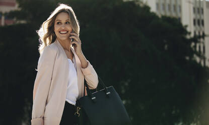 Real estate agent talking on phone while commuting. Businesswoman on phone call looking away and smiling. - JLPSF18393