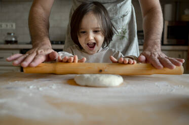 Happy boy with father rolling pizza dough in kitchen - ANAF00279