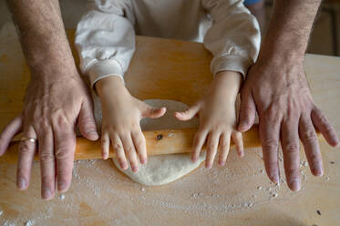 Hands of son and father rolling pizza dough in kitchen - ANAF00280