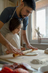 Junge mit Vater rollt Pizzateig in der Küche - ANAF00281