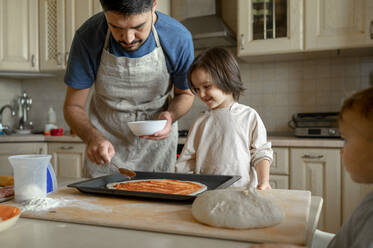 Happy boy with father preparing pizza at home - ANAF00282