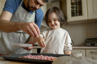 Vater mit Sohn beim Pizzabacken in der Küche zu Hause - ANAF00288