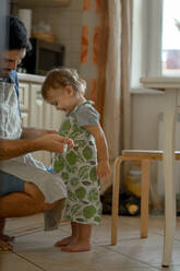 Vater bindet seinem kleinen Jungen in der Küche zu Hause eine Schürze um - ANAF00296
