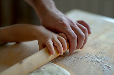 Hand des kleinen Jungen und Vater rollen Pizzateig in der Küche zu Hause - ANAF00298