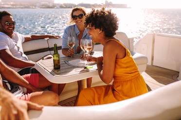 Group of young people having a boat party. Friends sitting at the back of a yacht and partying. - JLPSF18405