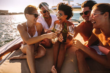 Multiracial group of people toasting drinks on the yacht deck and laughing. Cheerful men and woman partying on a boat. - JLPSF18411