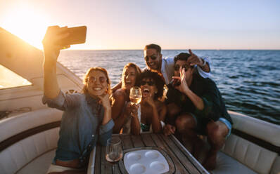 Fröhliche junge Leute posieren für ein Selfie auf einer Bootsparty. Verrückte Freunde, die eine Party auf einer privaten Yacht genießen und ein Selfie machen. - JLPSF18416