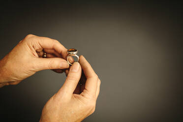 Nahaufnahme von Frau Goldschmied Hände suchen und prüfen einen Ring mit Edelstein. Schmuck-Designer Prüfung eines Ringes gegen grauen Hintergrund mit Kopie Raum. - JLPSF18420