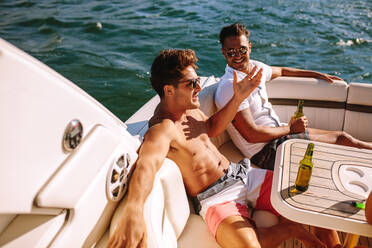 Young men sitting in a boat and having party. Male friends partying in a yacht. - JLPSF18506