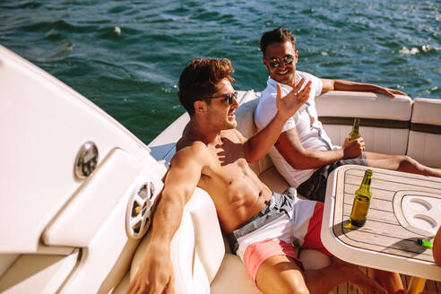 Junge Männer sitzen in einem Boot und feiern eine Party. Männliche Freunde feiern auf einer Jacht. - JLPSF18506