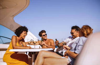 Group of diverse friends having a boat party. Happy young people sitting at the back of a yacht and drinking. - JLPSF18508