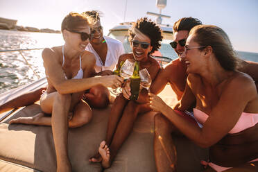 Eine Gruppe von Freunden amüsiert sich auf einer Yacht, trinkt Wein und lacht. Party auf dem Privatboot. - JLPSF18522
