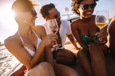 Schöne Frau mit Freunden, die sich auf einer Yacht amüsieren, Wein trinken und lächeln. Junge Leute, die auf einem privaten Boot feiern. - JLPSF18523
