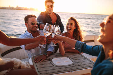 Junge Leute auf einer Yacht, die zusammen trinken. Eine Gruppe von Freunden stößt mit Getränken an und feiert eine Party auf einem Boot. - JLPSF18543