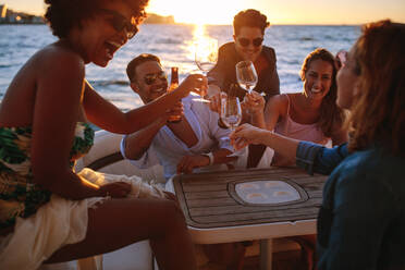 Group of smiling young people toasting at boat party during sunset. Men and women enjoying at a boat party. - JLPSF18545