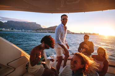 Happy friends drinking and having fun in boat party. Young rich people enjoying sunset boat party. - JLPSF18548