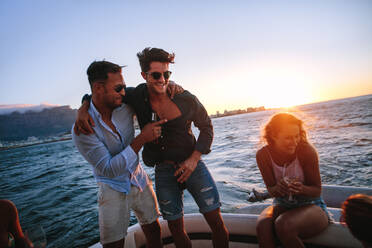 Young men having fun at boat part with friends. Young people enjoying in a sunset boat party. - JLPSF18551