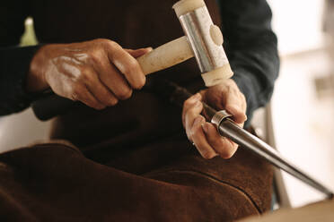 Juwelierin bei der Arbeit mit dem Hammer an einem Silberring in ihrer Werkstatt. Juwelierin bei der Herstellung eines Rings aus einem Silberrohling in ihrer Werkstatt. - JLPSF18566