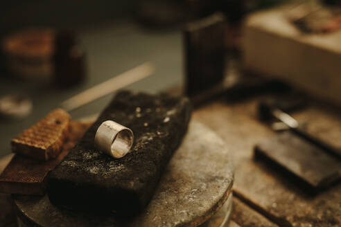Ring auf der Werkbank eines Juweliers mit kleinen Metallstücken an der Verbindungsstelle, bereit zum Löten. Herstellung eines Rings in einer Schmuckwerkstatt. - JLPSF18574
