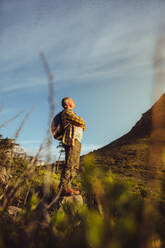 Low angle view of a trekker standing on a hill wearing backpacking enjoying the scenery. Wanderer steht auf einem Hügel und genießt die Natur. - JLPSF18650