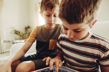 Ein Junge spielt ein Spiel auf einem Tablet-PC, während sein Freund zuschaut. - JLPSF18701