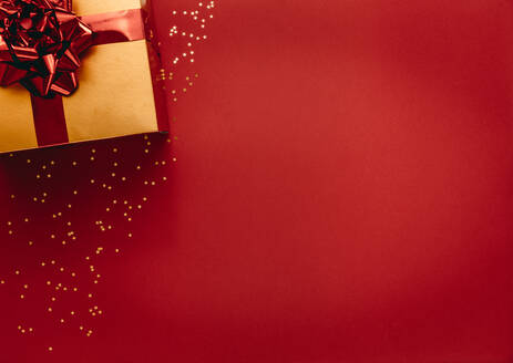 Goldene farbige Geschenk-Box mit Sternen auf rotem Hintergrund. Draufsicht auf Weihnachtsgeschenk mit Sternen flach auf rotem Hintergrund legen. - JLPSF18732