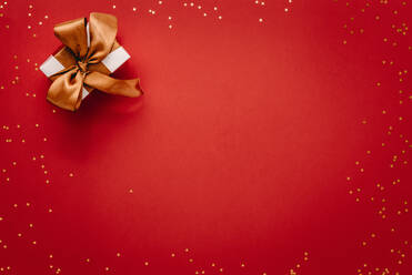 Kleine Geschenkbox mit Sternen auf rotem Hintergrund. Draufsicht auf ein Weihnachtsgeschenk mit Sternen, flat lay auf rotem Hintergrund. - JLPSF18733