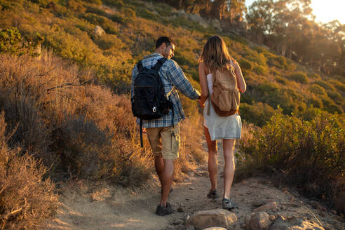 Couple of hikers walking down the hill. Man and woman with backpack walking down the mountain trail. - JLPSF18757