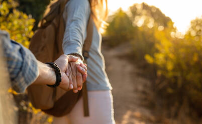 Nahaufnahme eines jungen Paares auf einem Wanderausflug. Ausgeschnittenes Bild eines jungen Mannes und einer Frau, die sich beim Wandern auf einem Bergpfad an den Händen halten. - JLPSF18778