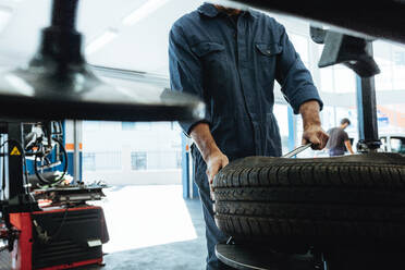 Mechanic removes car tire service station. Man working on machine for removing rubber from the wheel disc. - JLPSF18810