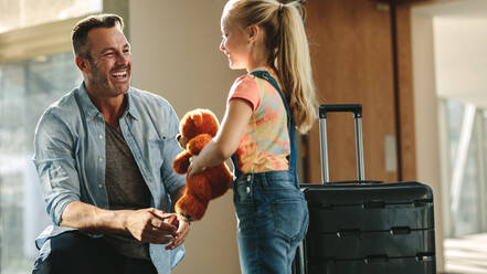 Tochter mit Teddybär, die ihren Vater an der Tür empfängt, wenn er von einer Reise zurückkommt. Tochter, die ihren Vater, der gerade von einer Tournee zurückkommt, mit einer Reisetasche begrüßt. - JLPSF18870