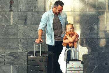 Vater und Tochter stehen zusammen mit ihrem Gepäck am Flughafen. Eine Familie mit zwei Kindern auf dem Weg in den Urlaub. - JLPSF18885