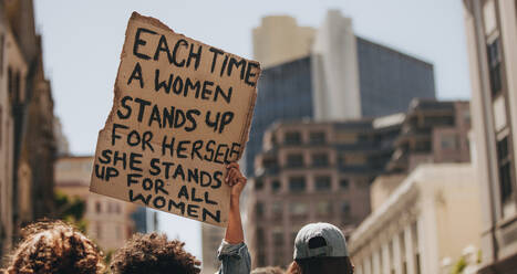 Gruppe von Demonstranten auf der Straße mit einem Schild, auf dem steht, dass jedes Mal, wenn eine Frau für sich selbst eintritt, sie für alle Frauen eintritt. Aktivistin demonstriert Frauenpower. - JLPSF18924