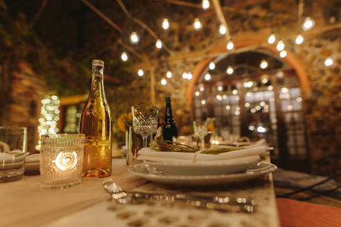Tisch für Dinnerparty im Freien am Abend mit Lichtern im Hintergrund. Schöner gedeckter Tisch für eine große Party in der Nacht. - JLPSF18957