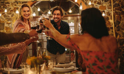 Freunde machen eine große Party in der Nacht. Eine Gruppe von Menschen stößt während einer Dinnerparty mit Wein an. - JLPSF18960