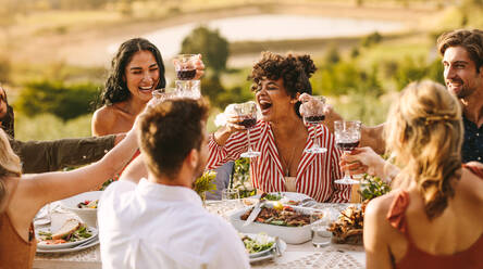 Eine Gruppe fröhlicher Freunde, die bei einer Dinnerparty Wein trinken. Multi-ethnische Menschen, die sich im Freien treffen. - JLPSF19002