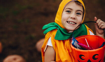 Close up Porträt von niedlichen kleinen Mädchen in Halloween-Kostüm hält Kürbis Eimer im Freien im Park. Kleines Mädchen Kind für Süßes oder Saures auf Halloween. - JLPSF19023