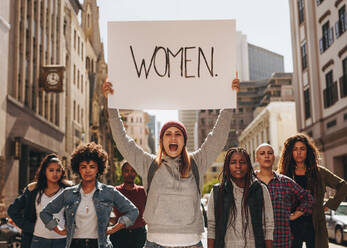 Eine wütende Frau schreit mit einem handgeschriebenen Protestschild beim Frauenmarsch. Eine Gruppe verschiedener Frauen demonstriert im Freien auf einer Straße in der Stadt. - JLPSF19034